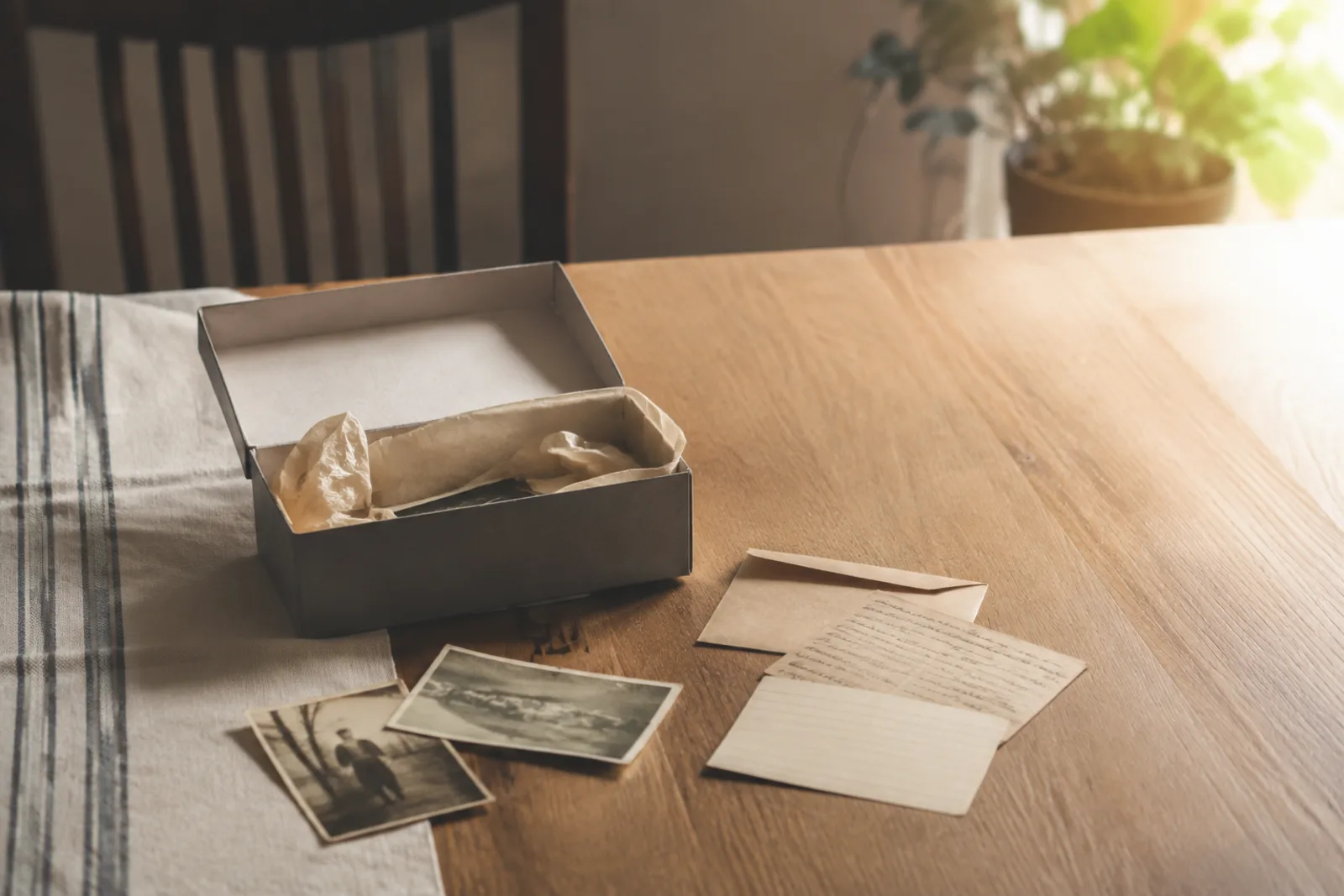 Sparse box of inherited photographs, an envelope and an unreadable handwritten card on a table