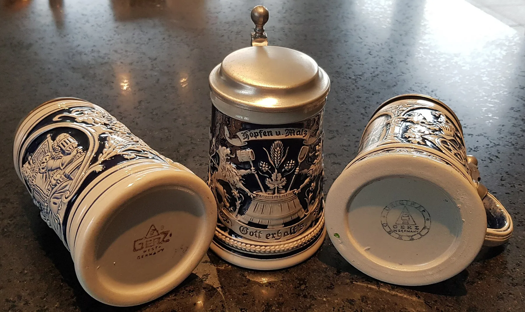 Three blue-and-cream salt-glazed German ceramic beer steins, including one with a hinged lid