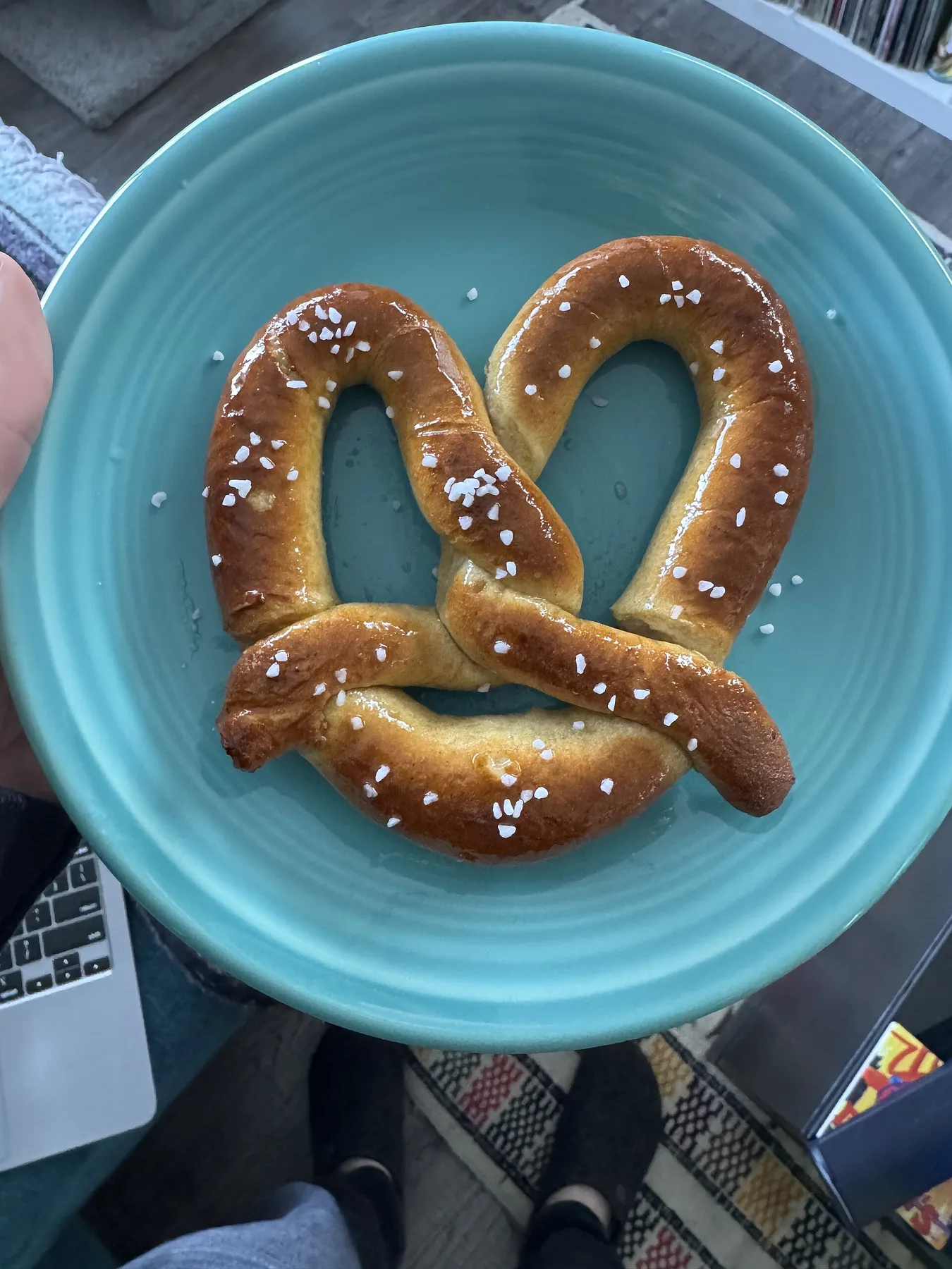 Freshly baked soft pretzel with a glossy brown crust and coarse salt on a blue plate