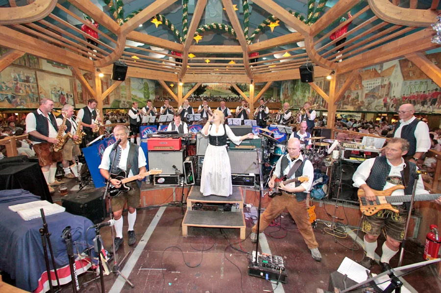 Brass musicians performing for guests seated at shared festival tables