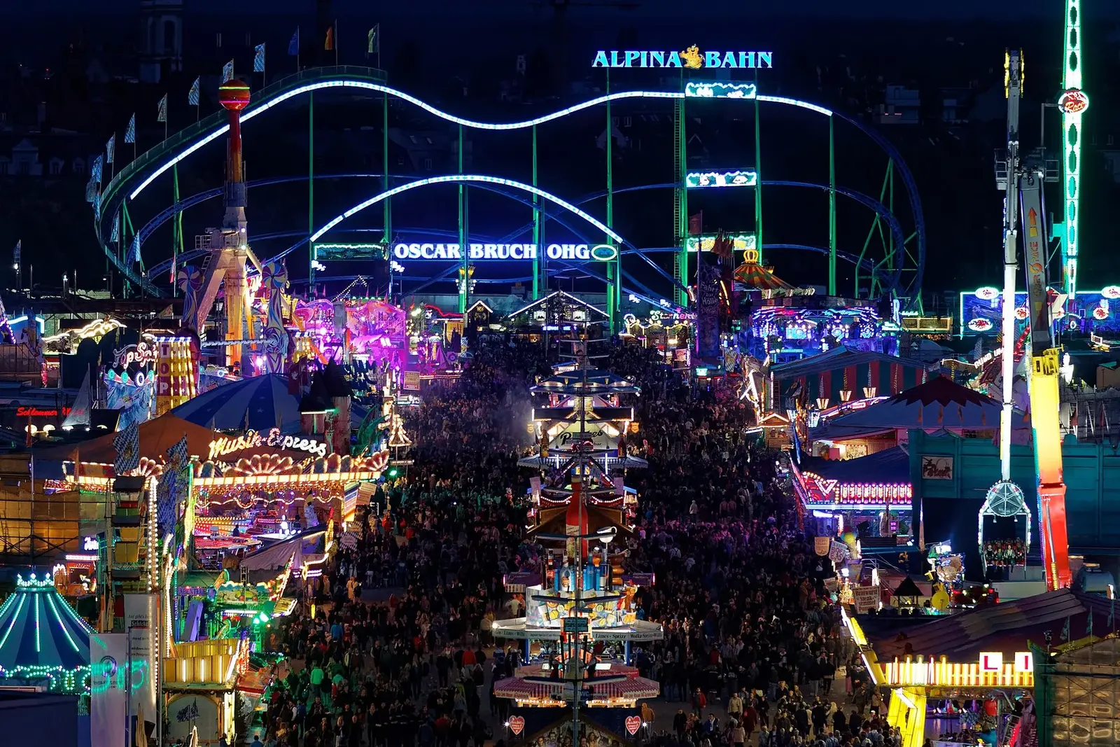 Crowded Munich Oktoberfest fairground illuminated after dark