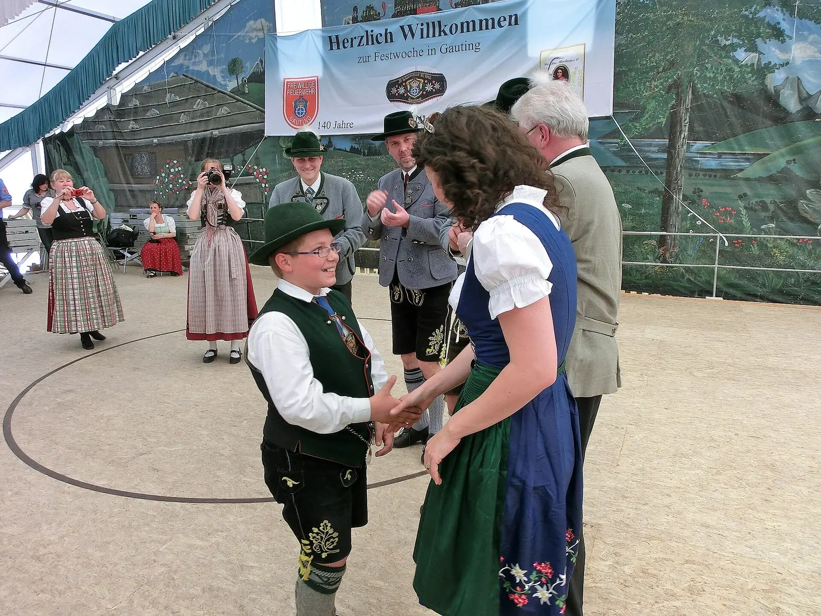 Children and adults wearing varied Bavarian traditional clothing at a community festival