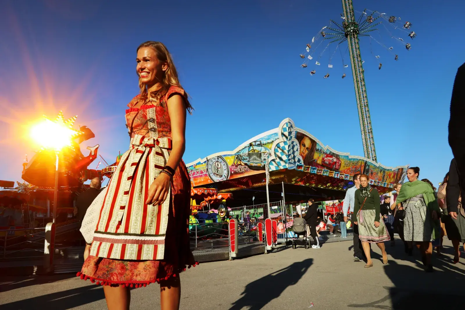 Woman wearing a dirndl in front of an amusement ride at Munich Oktoberfest
